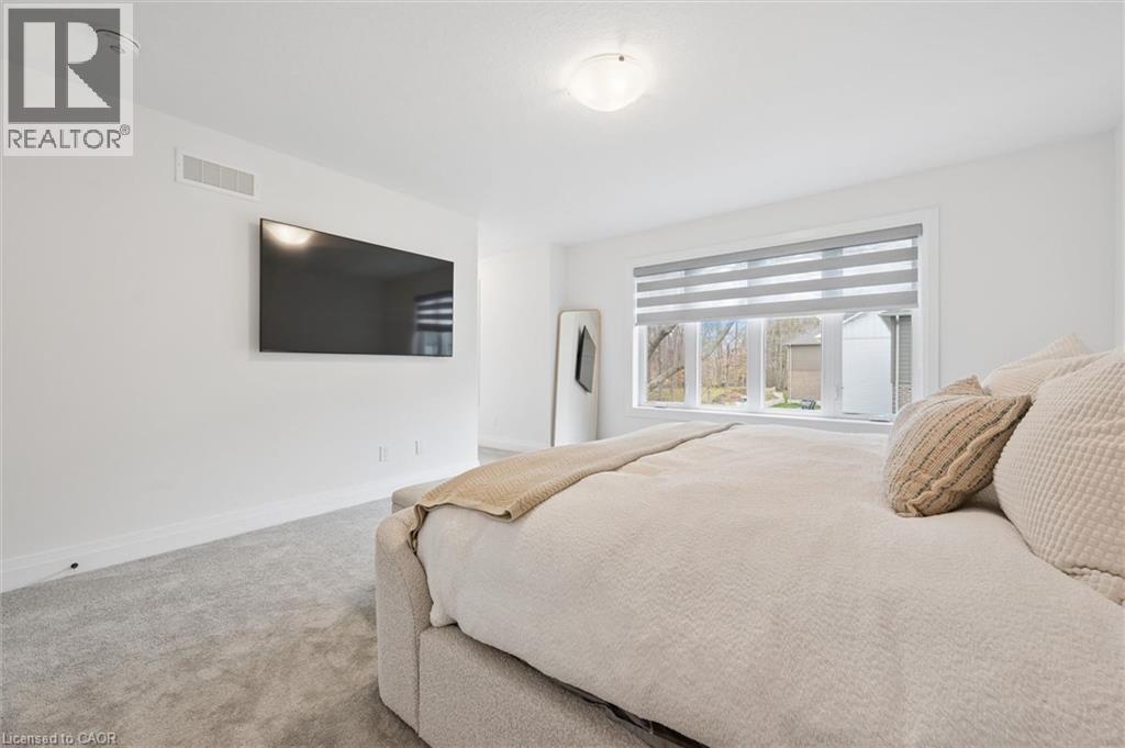 Bright bedroom featuring a wall-mounted television, a large window with privacy blinds, and plush carpeting - 213 Fallowfield Drive, Kitchener, ON - Indoor Photo Showing Bedroom