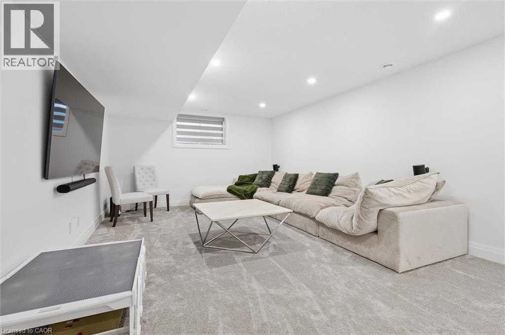 Spacious recreational area featuring recessed lighting, a large window with horizontal blinds, and light-toned wall-to-wall carpeting - 213 Fallowfield Drive, Kitchener, ON - Indoor