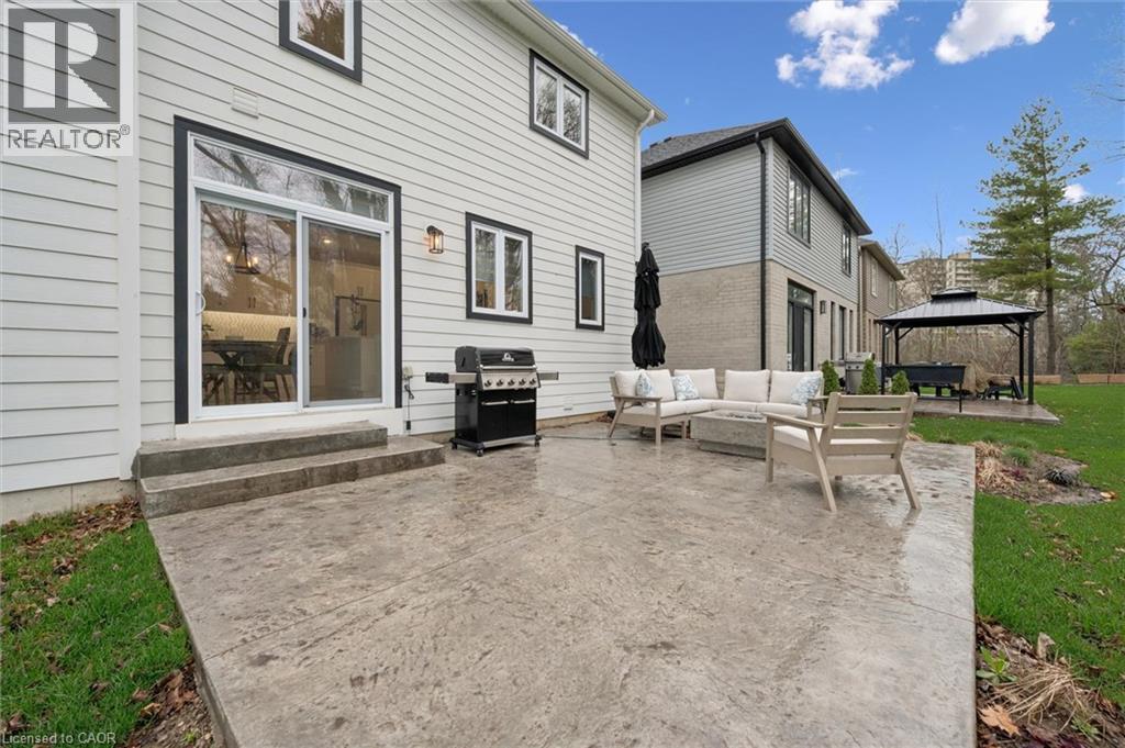Expansive stamped concrete patio with direct access to interior spaces via sliding glass doors - 213 Fallowfield Drive, Kitchener, ON - Outdoor With Exterior