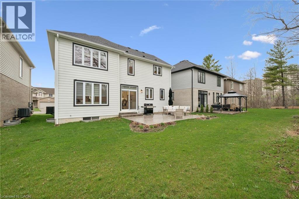 Expansive backyard featuring a large green lawn, paver patio, and sliding glass door access to the interior - 213 Fallowfield Drive, Kitchener, ON - Outdoor With Exterior