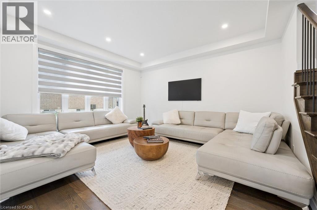 Bright living space featuring dark wood-finish flooring, recessed lighting, and a tray ceiling - 213 Fallowfield Drive, Kitchener, ON - Indoor Photo Showing Living Room