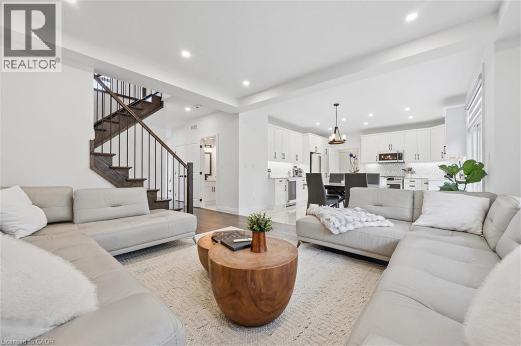 Bright open-concept living space featuring recessed lighting, a modern staircase with dark wood treads and iron balusters, and wood-finish flooring - 213 Fallowfield Drive, Kitchener, ON - Indoor Photo Showing Living Room