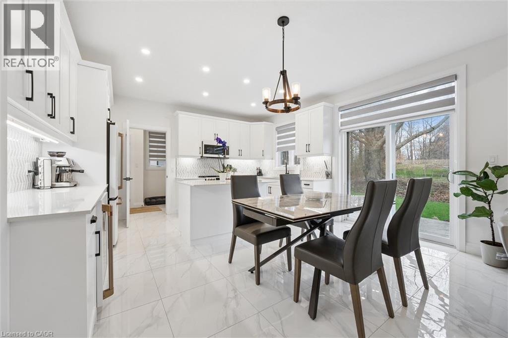 Bright kitchen and dining area featuring white cabinetry, a patterned tile backsplash, and light-toned flooring - 213 Fallowfield Drive, Kitchener, ON - Indoor