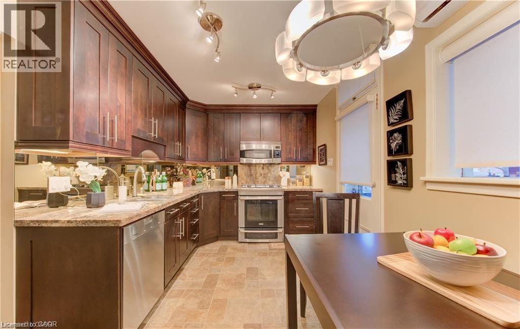 The kitchen features extensive dark wood cabinetry, granite countertops, and stainless steel appliances - 48 Dupont Street, Waterloo, ON - Indoor Photo Showing Kitchen