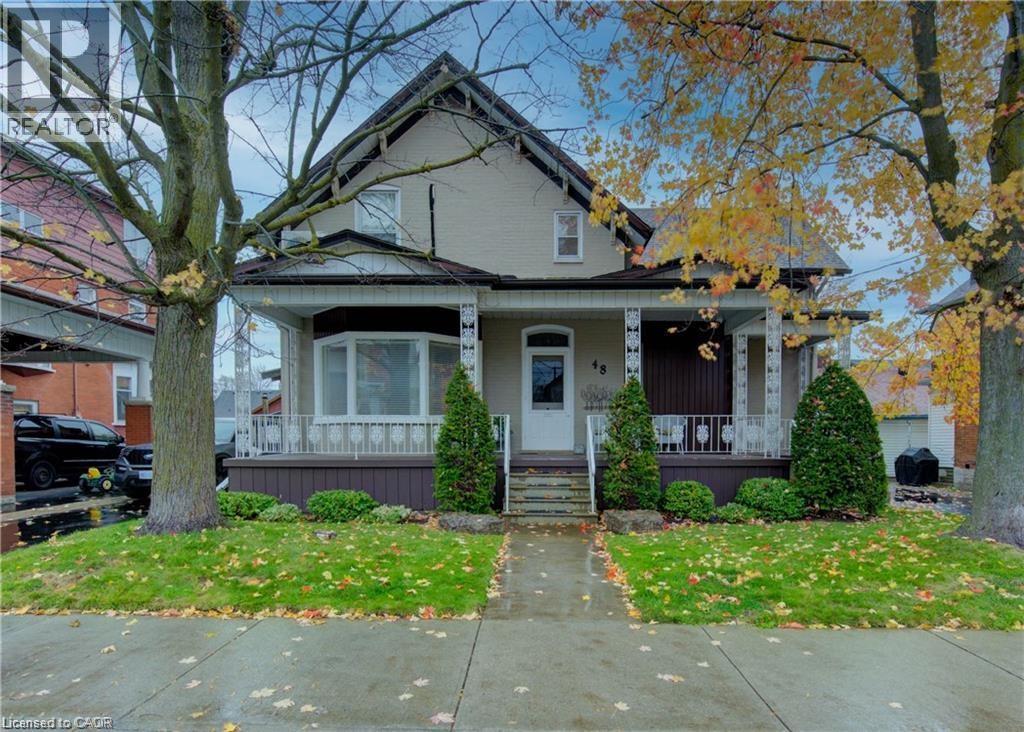 The property features a charming exterior with a covered front porch and mature trees - 48 Dupont Street, Waterloo, ON - Outdoor With Deck Patio Veranda With Facade
