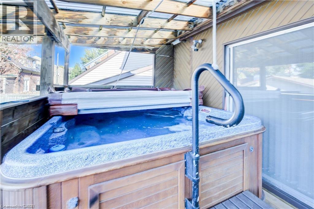 This property features a hot tub with a wooden exterior and a protective cover, situated under a wooden pergola - 48 Dupont Street, Waterloo, ON - With Exterior