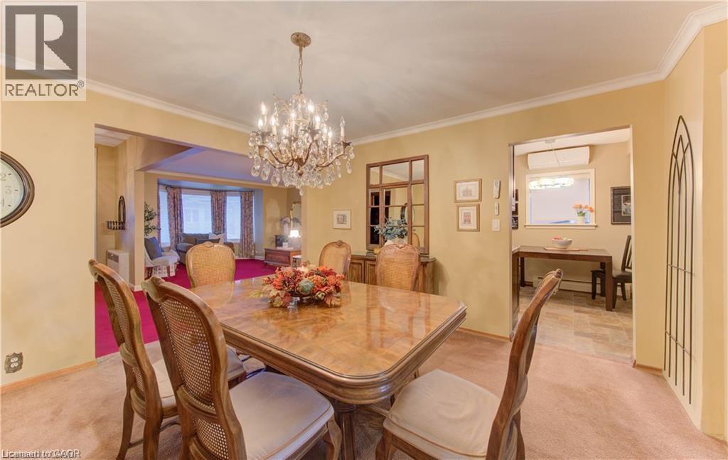 The dining area features a decorative chandelier and carpeted flooring, with a separate space visible through an archway - 48 Dupont Street, Waterloo, ON - Indoor Photo Showing Dining Room