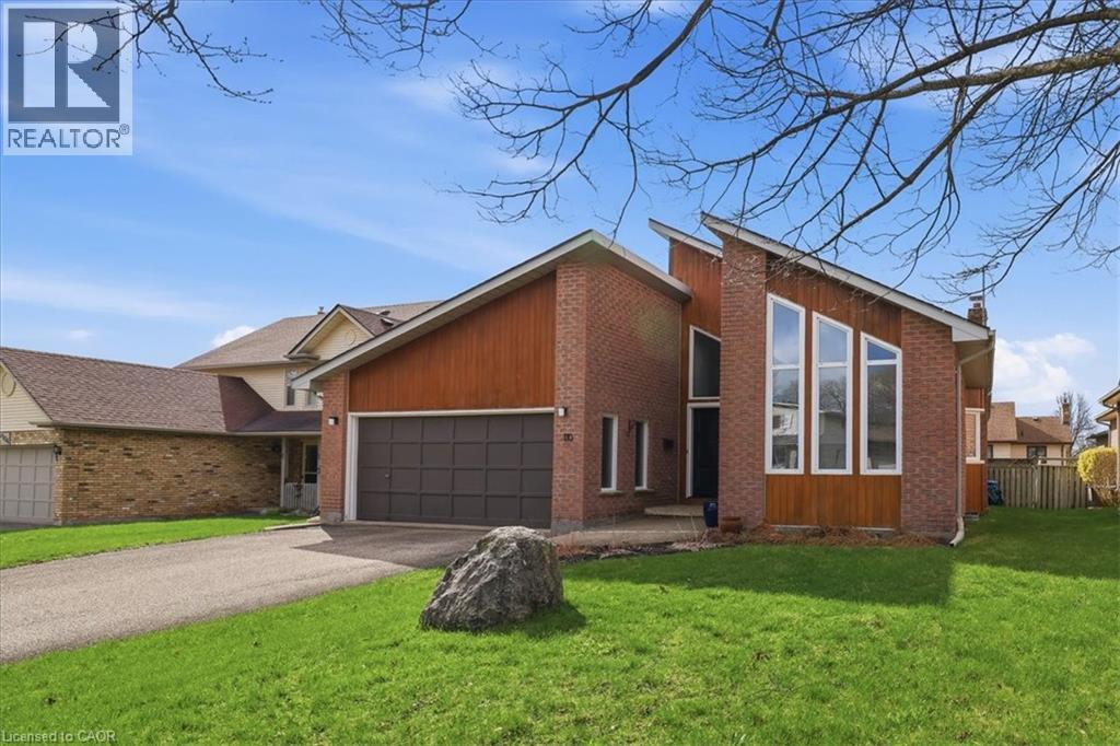 The property features a brick exterior with wood paneling accents, a two-car garage, and a well-maintained front lawn - 110 Milton Avenue, Cambridge, ON - Outdoor