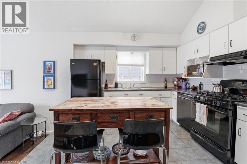 The property features a kitchen with white cabinetry, black appliances, and a wood-topped island - 110 Milton Avenue, Cambridge, ON - Indoor Photo Showing Kitchen