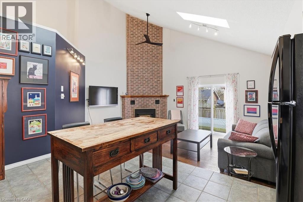 This bright living area features a brick fireplace, a skylight, and direct access to the outdoor space through sliding glass doors - 110 Milton Avenue, Cambridge, ON - Indoor Photo Showing Other Room