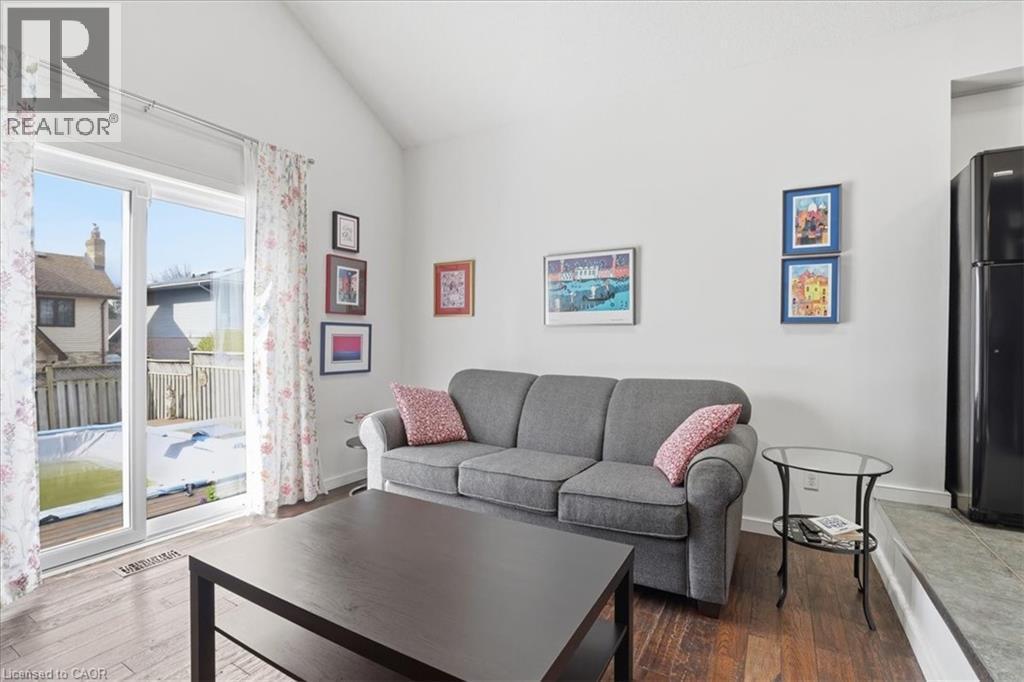Living area featuring hardwood style flooring, a vaulted ceiling, and sliding glass doors leading to the exterior - 110 Milton Avenue, Cambridge, ON - Indoor Photo Showing Living Room
