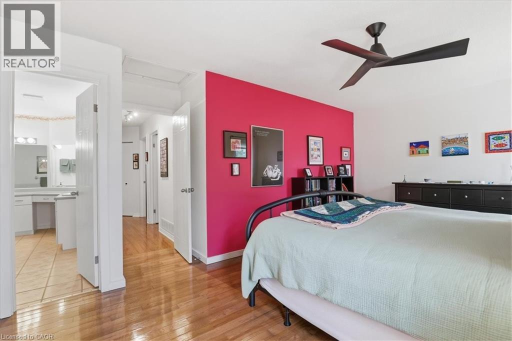This bedroom features hardwood floors, a ceiling fan, and a vibrant accent wall - 110 Milton Avenue, Cambridge, ON - Indoor Photo Showing Bedroom