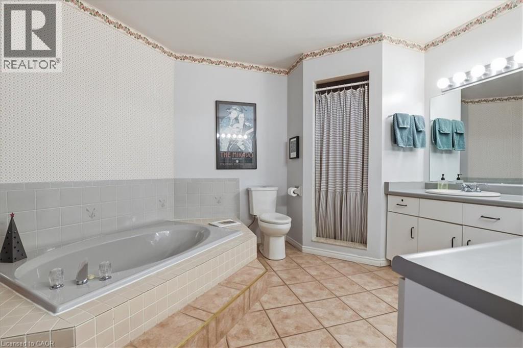 Bathroom featuring a built-in bathtub with tiled surround, a standing shower, and a vanity with an integrated sink and mirror - 110 Milton Avenue, Cambridge, ON - Indoor Photo Showing Bathroom
