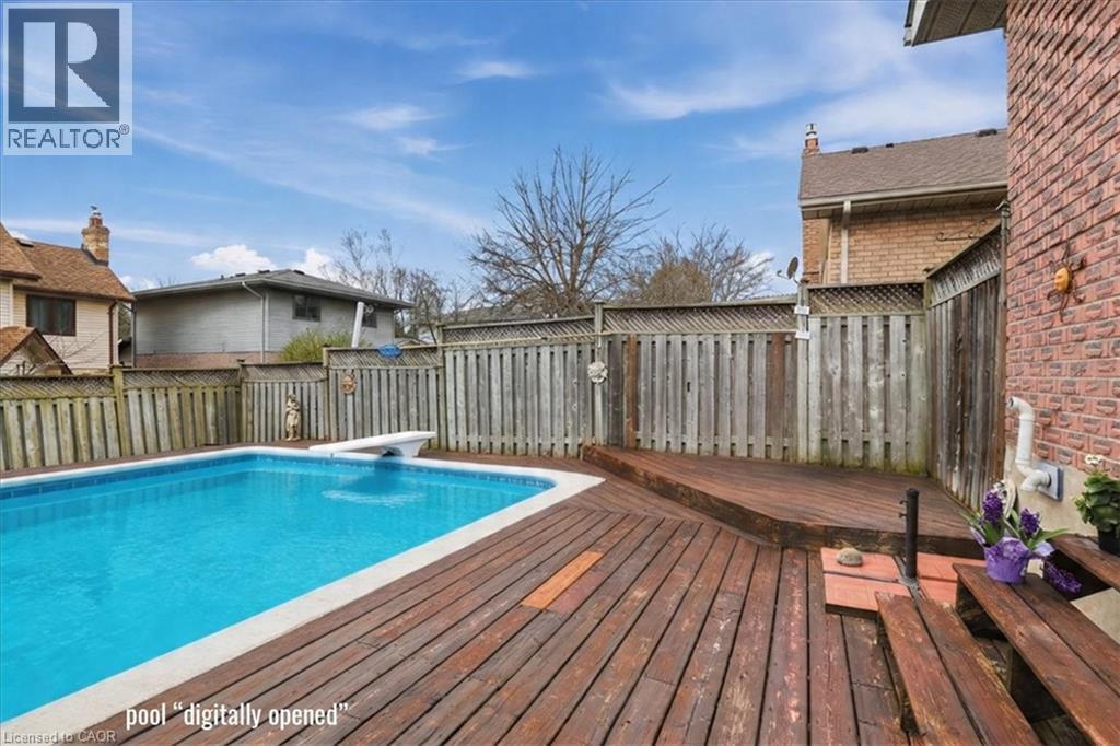 The property features a private outdoor swimming pool with a diving board, surrounded by a wooden deck - 110 Milton Avenue, Cambridge, ON - Outdoor With Above Ground Pool