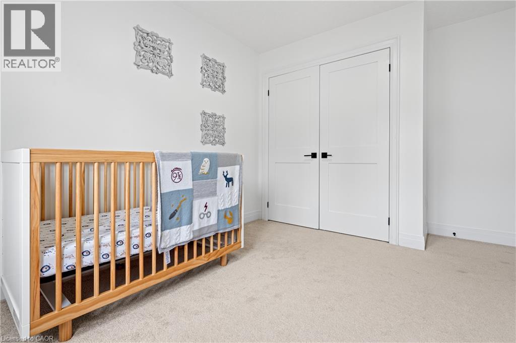 Carpeted room featuring white walls, a white baseboard, and a pair of white double doors with matte black hardware - 1026 Wright Drive, Midland, ON - Indoor Photo Showing Bedroom