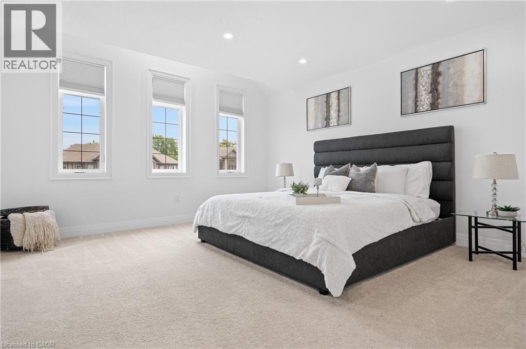 Bright room featuring three tall windows with white frames and blinds, recessed lighting, neutral tone carpet, and white baseboards - 1026 Wright Drive, Midland, ON - Indoor Photo Showing Bedroom