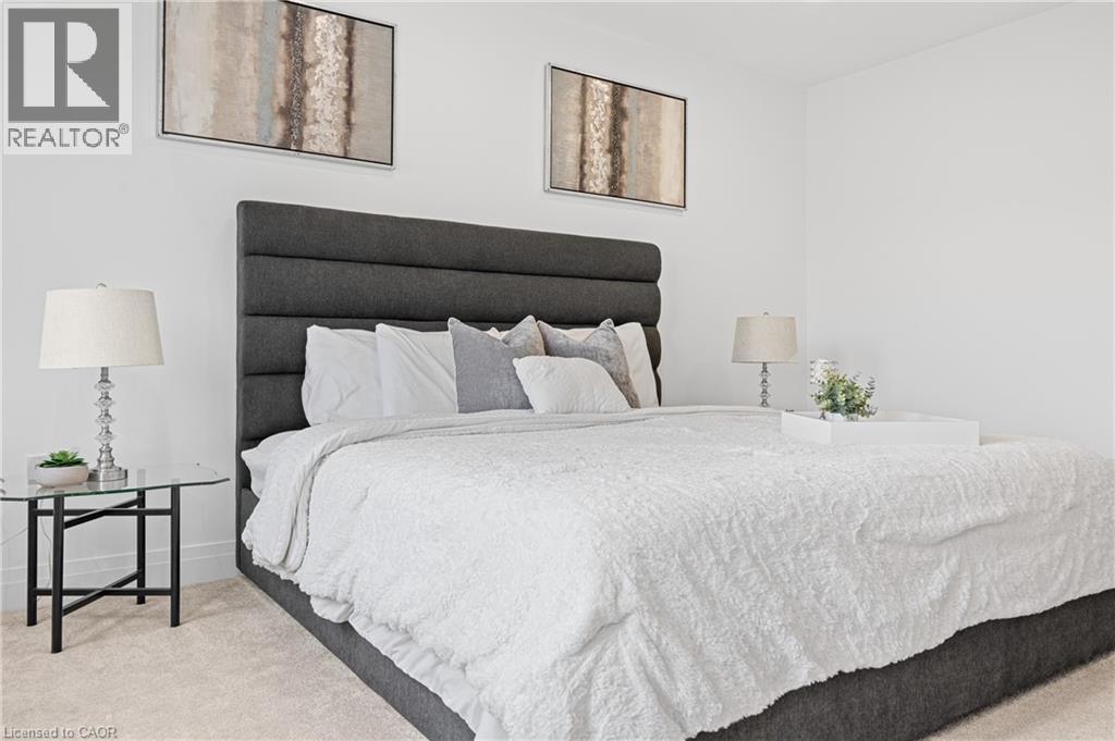 Spacious sleeping area featuring a tall, upholstered headboard, crisp white walls, and soft carpet flooring - 1026 Wright Drive, Midland, ON - Indoor Photo Showing Bedroom