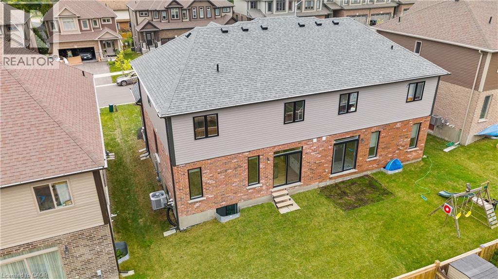 Rear exterior featuring a brick and siding facade, multiple large windows, and two sliding glass doors opening to a green lawn - 1026 Wright Drive, Midland, ON - Outdoor