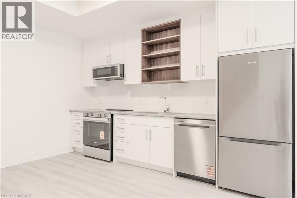 Kitchen featuring white cabinetry, stainless steel appliances including a refrigerator, range, microwave, and dishwasher, and light-colored countertops - 144 Everett Common, St. Catharines, ON - Indoor Photo Showing Kitchen