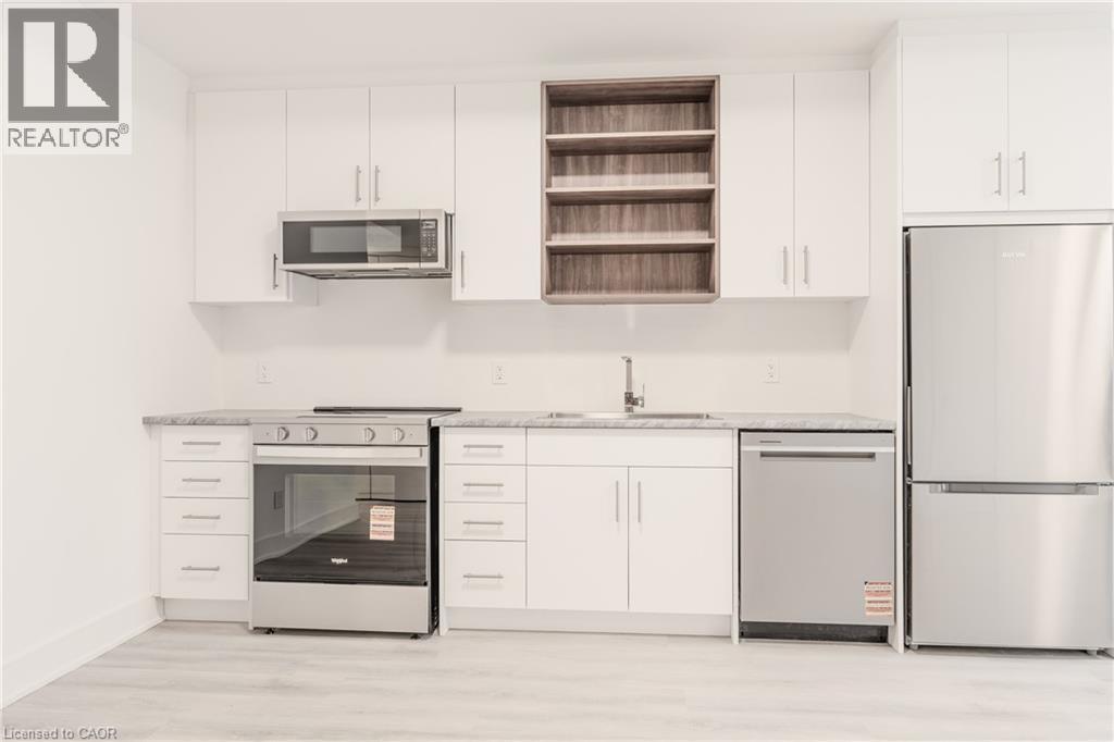 The kitchen features white cabinetry, stainless steel appliances, and light-colored countertops - 144 Everett Common, St. Catharines, ON - Indoor Photo Showing Kitchen
