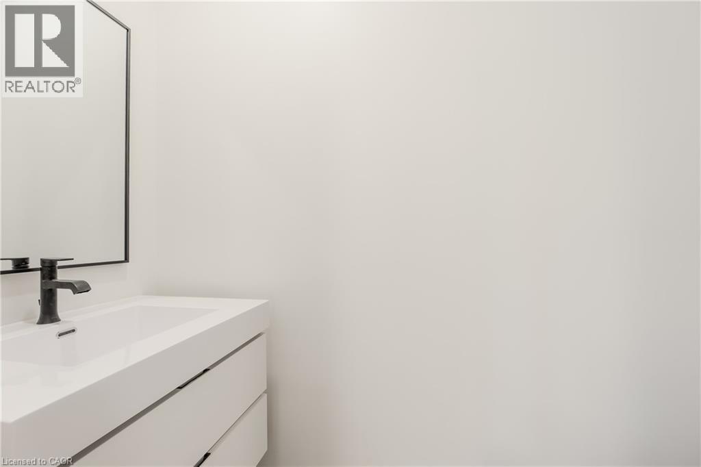 Bathroom vanity featuring a white rectangular sink, a black faucet, and a mirror with a black frame - 144 Everett Common, St. Catharines, ON - Indoor Photo Showing Bathroom
