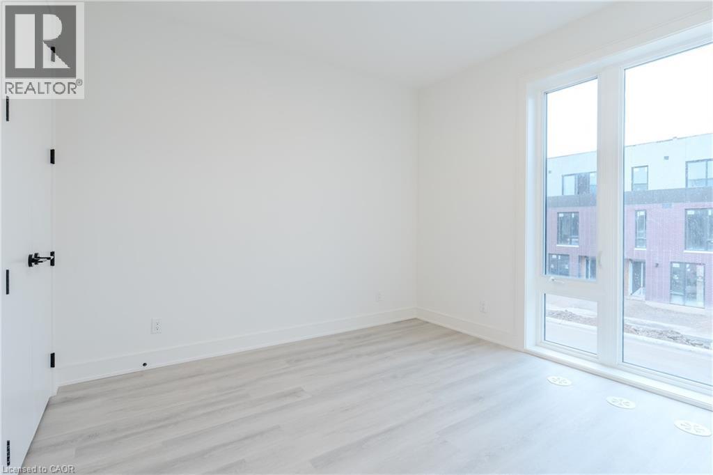 Well-lit room featuring light-toned flooring, white walls, and a large window - 144 Everett Common, St. Catharines, ON - Indoor Photo Showing Other Room