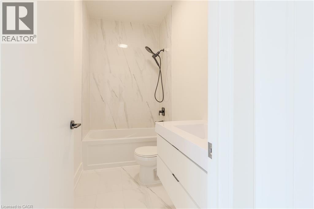 Bathroom featuring a white bathtub, toilet, and vanity with a rectangular sink - 144 Everett Common, St. Catharines, ON - Indoor Photo Showing Bathroom
