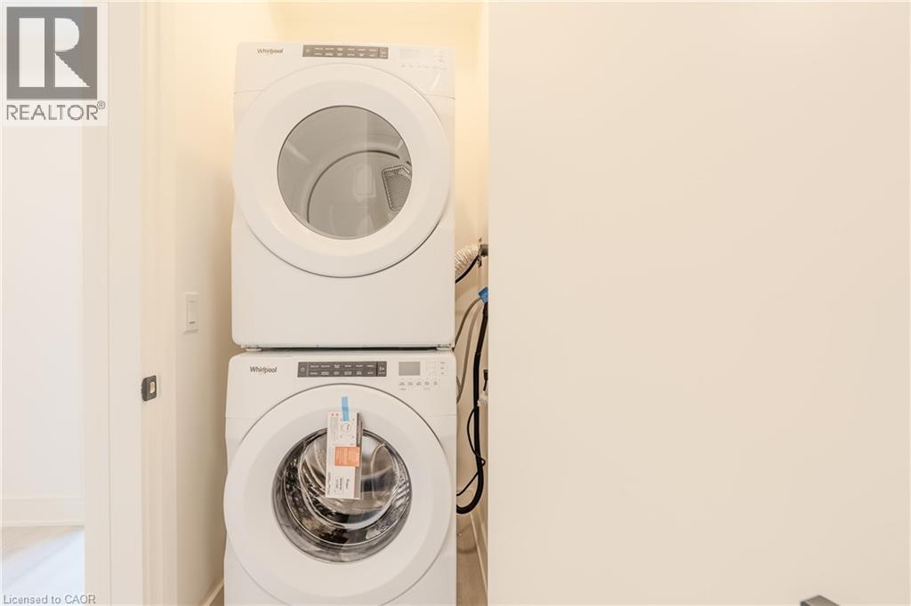 Dedicated laundry area featuring a white stacked washer and dryer unit - 144 Everett Common, St. Catharines, ON - Indoor Photo Showing Laundry Room