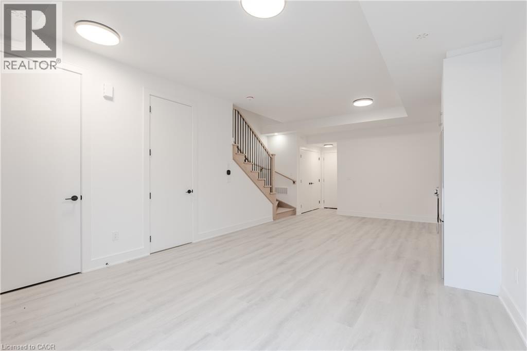 Spacious interior featuring light-toned flooring and white walls, complemented by modern flush-mount lighting fixtures - 144 Everett Common, St. Catharines, ON - Indoor Photo Showing Other Room