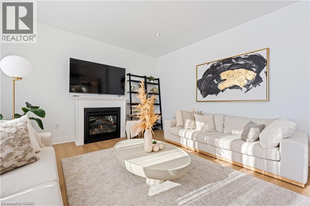 Living area featuring light wood-style flooring and a glass covered fireplace - 66 Cesar Place, Ancaster, ON - Indoor Photo Showing Living Room With Fireplace