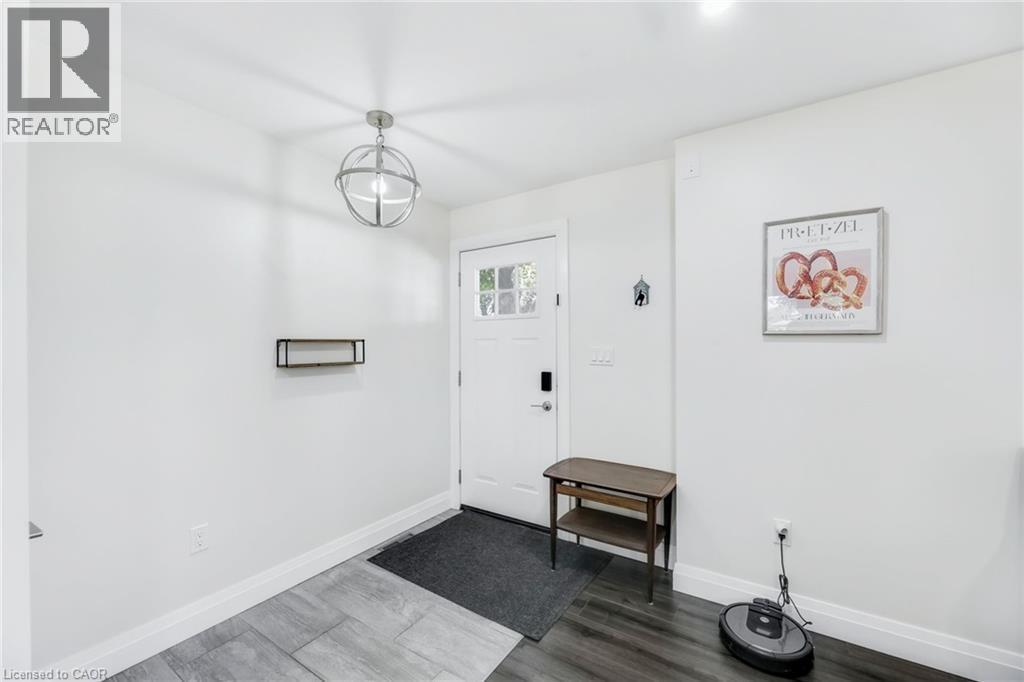 Entryway featuring a white paneled door with glass inserts, a contemporary spherical pendant light, and two-tone wood-finish flooring - 18 Tweedsmuir Avenue, London, ON - Indoor Photo Showing Other Room