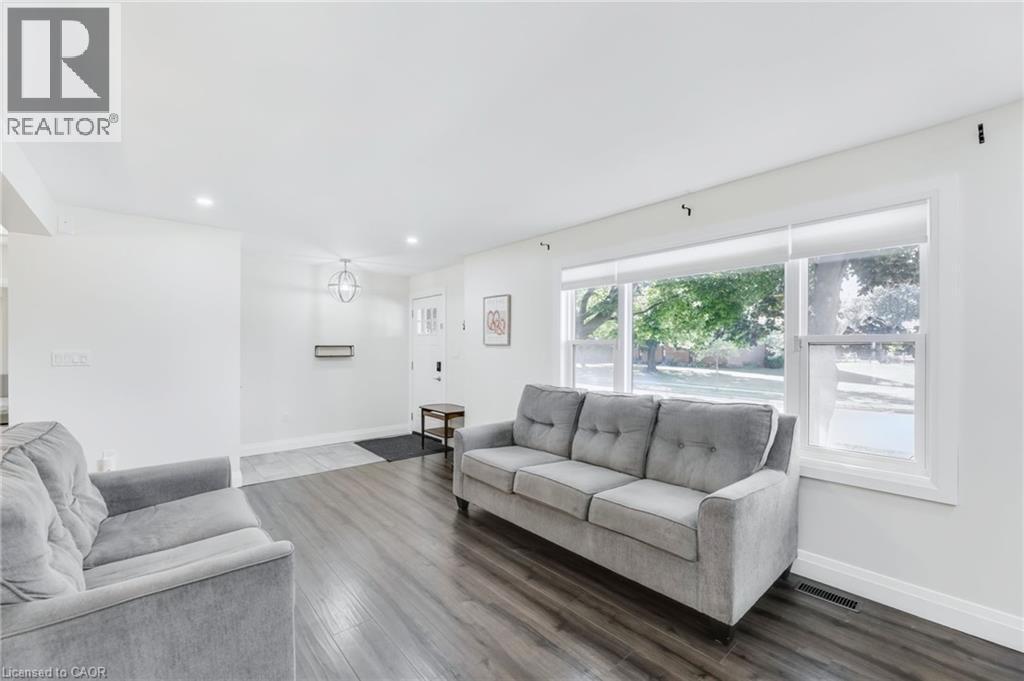 Bright living area featuring wood-finish flooring, recessed lighting, and a large front window with roller shades - 18 Tweedsmuir Avenue, London, ON - Indoor Photo Showing Living Room