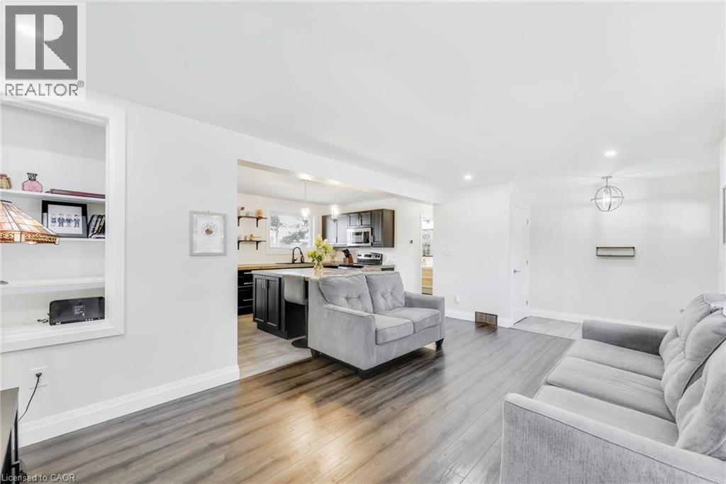 Open-concept living area featuring wood-finish flooring, recessed lighting, and a built-in shelving unit - 18 Tweedsmuir Avenue, London, ON - Indoor Photo Showing Living Room