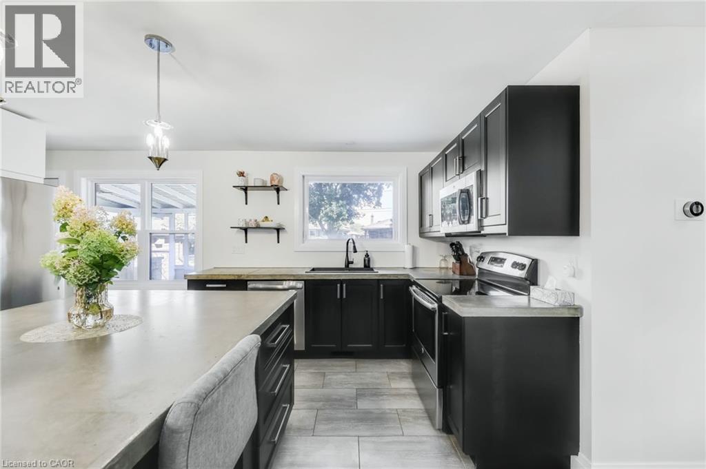Modern kitchen featuring black cabinetry, light-toned countertops, and stainless steel appliances - 18 Tweedsmuir Avenue, London, ON - Indoor Photo Showing Kitchen
