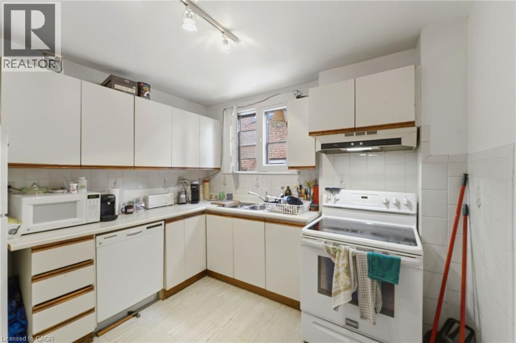 Functional kitchen with ample storage, featuring white cabinetry, a built-in dishwasher, and a white electric range - 509 Aberdeen Avenue, Hamilton, ON - Indoor Photo Showing Kitchen With Double Sink
