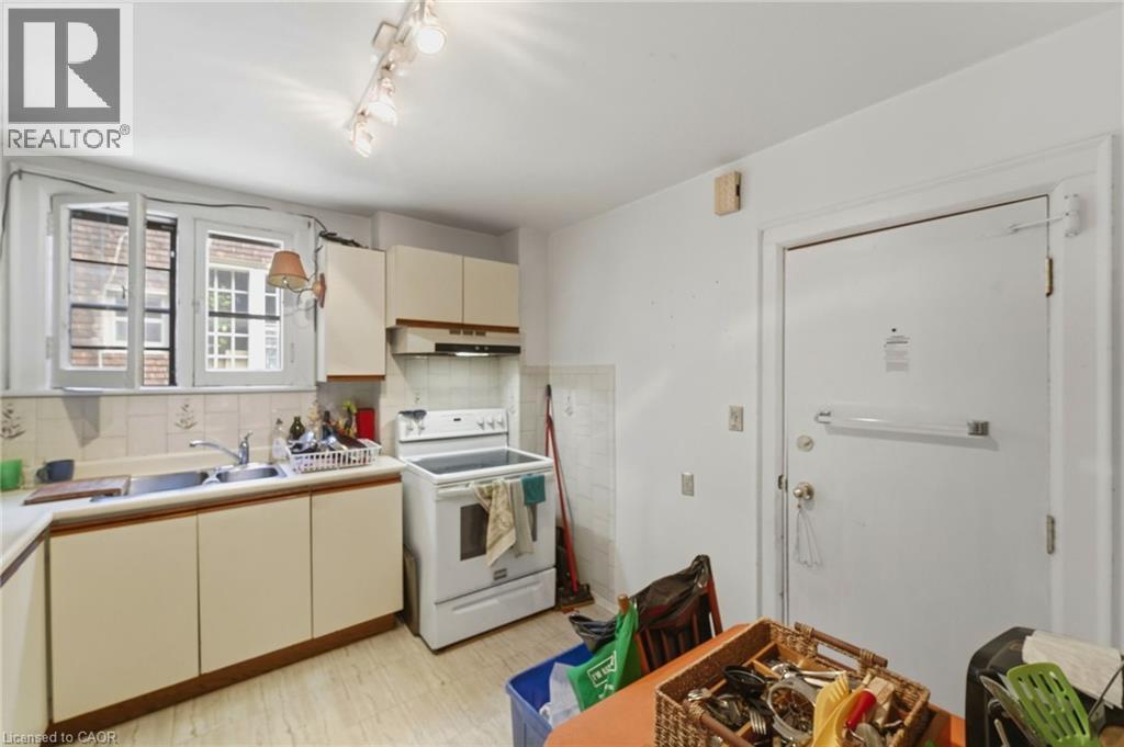Kitchen featuring a dual-basin stainless steel sink, white ceramic tile backsplash, and light-toned cabinetry - 509 Aberdeen Avenue, Hamilton, ON - Indoor Photo Showing Kitchen With Double Sink