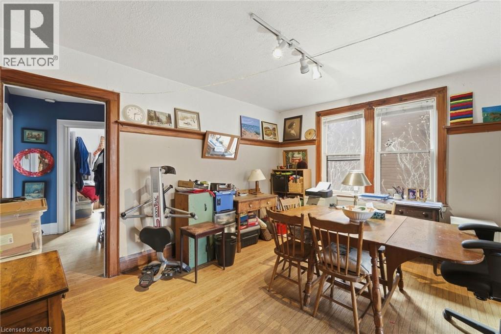 Spacious room featuring wood-finish flooring, white walls with a chair rail, and natural wood trim around windows and doorways - 509 Aberdeen Avenue, Hamilton, ON - Indoor