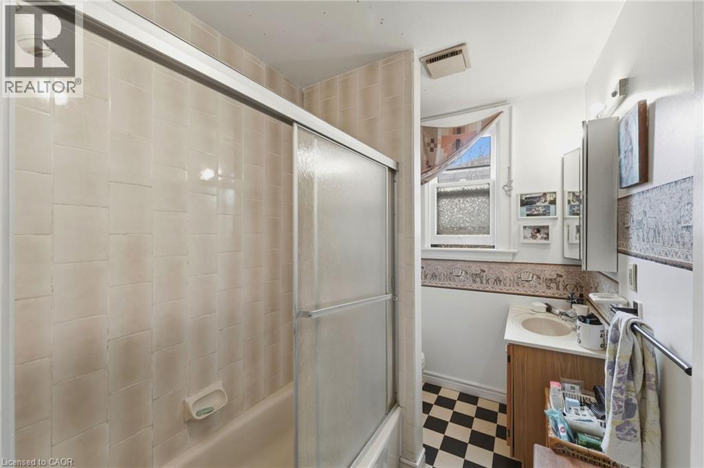Bathroom featuring a tiled shower with sliding glass doors, a vanity with a built-in sink, a wall-mounted medicine cabinet, and checkerboard floor tiles - 509 Aberdeen Avenue, Hamilton, ON - Indoor Photo Showing Other Room