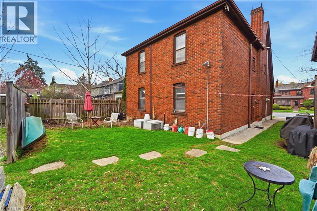 Brick exterior featuring multiple windows, a foundation perimeter, and a partial concrete walkway - 509 Aberdeen Avenue, Hamilton, ON - Outdoor