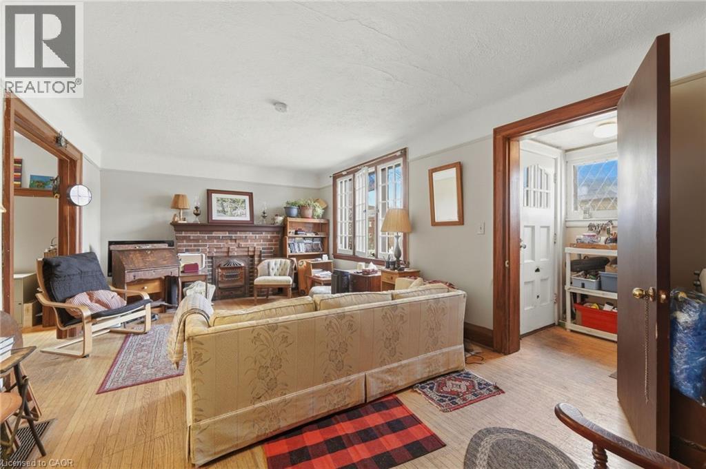 Living space featuring wood-finish flooring, a brick fireplace, white trim, wood door frames, and multi-pane windows - 509 Aberdeen Avenue, Hamilton, ON - Indoor With Fireplace