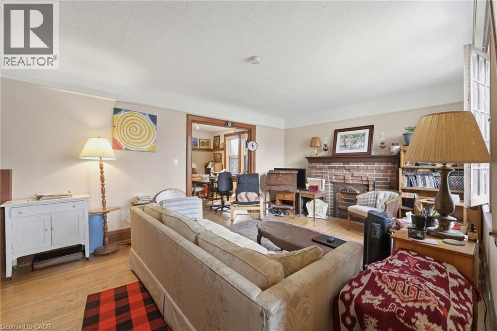 Living room featuring wood-finish flooring, a brick fireplace with a wood mantel, and broad baseboards - 509 Aberdeen Avenue, Hamilton, ON - Indoor Photo Showing Living Room With Fireplace