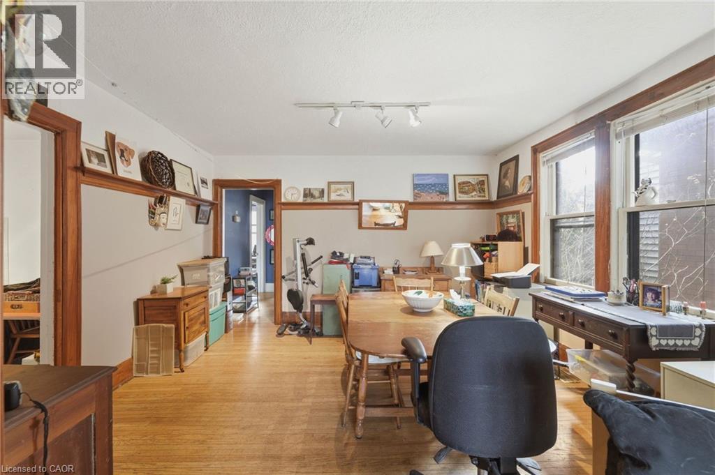 Spacious room featuring wood-finish flooring, white walls with a chair rail, natural wood trim, and multiple windows providing natural light - 509 Aberdeen Avenue, Hamilton, ON - Indoor