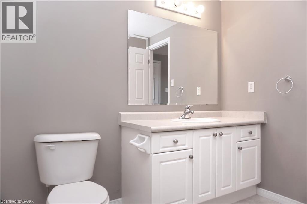 Bathroom featuring a white vanity with a single sink, an integrated countertop, and a large mirror - 40 Madeleine Street, Kitchener, ON