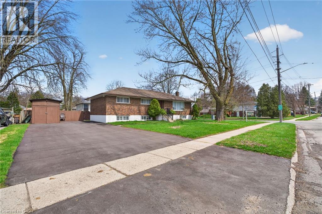 Brick-clad residence featuring a paved driveway, front lawn, and mature trees - 53 Nicklin Crescent, Guelph, ON - Outdoor