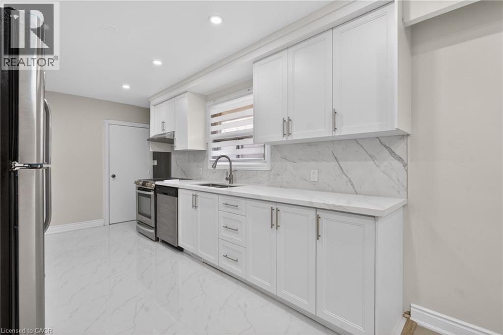 Kitchen featuring white shaker-style cabinetry, stainless steel appliances, a white marble-patterned backsplash, and a coordinating countertop - 53 Nicklin Crescent, Guelph, ON - Indoor Photo Showing Kitchen