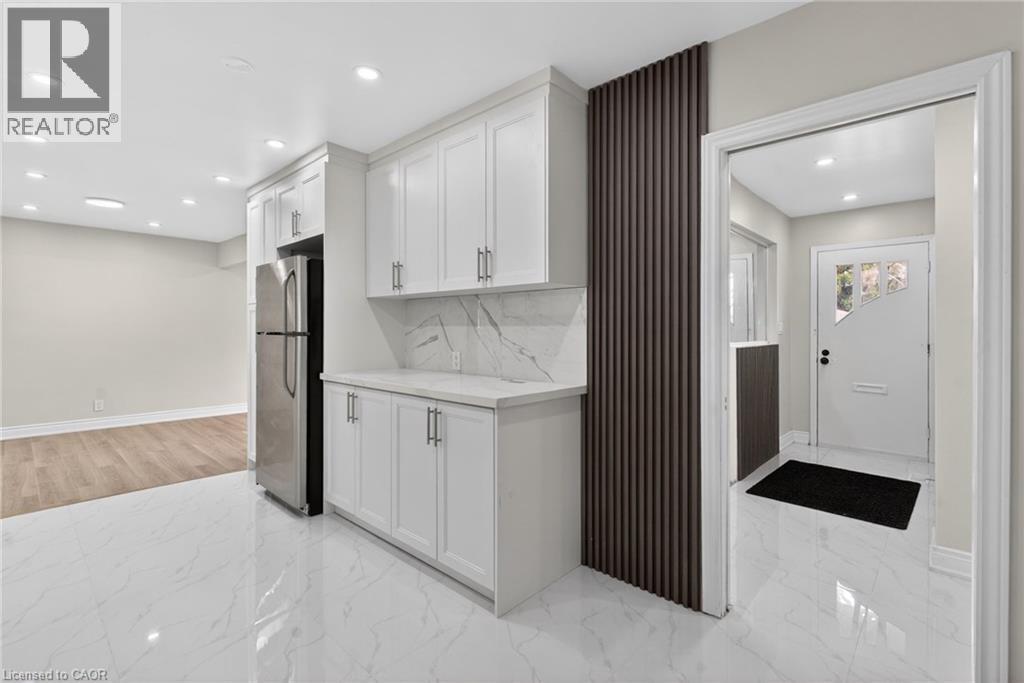 Kitchenette featuring white shaker cabinetry, stainless steel refrigerator, white countertop, and marble-look backsplash - 53 Nicklin Crescent, Guelph, ON - Indoor Photo Showing Other Room