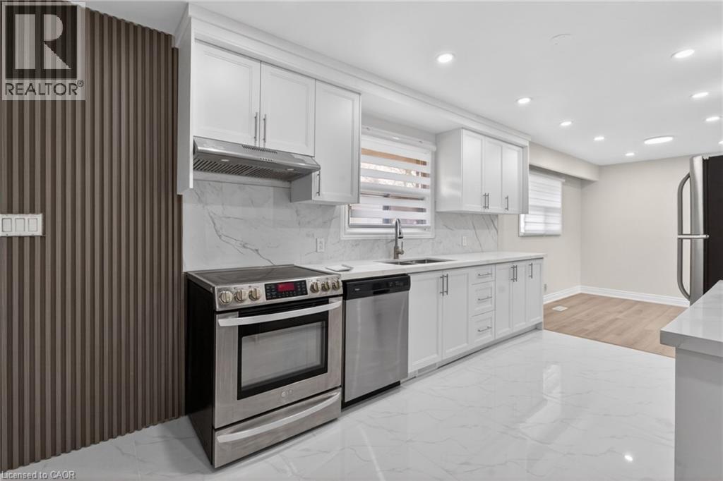Contemporary kitchen featuring white cabinetry, stainless steel appliances, a white stone-look backsplash, and integrated ceiling lighting - 53 Nicklin Crescent, Guelph, ON - Indoor Photo Showing Kitchen With Stainless Steel Kitchen