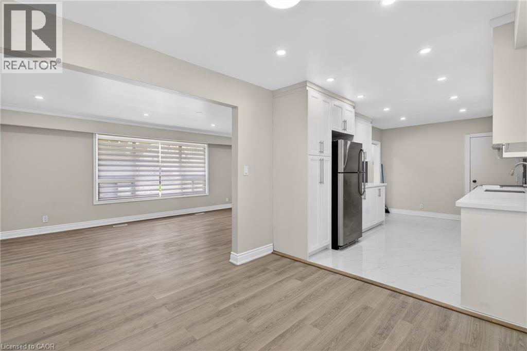 Bright open-concept living space featuring wood-finish flooring in the living area and white tile flooring in the kitchen - 53 Nicklin Crescent, Guelph, ON - Indoor