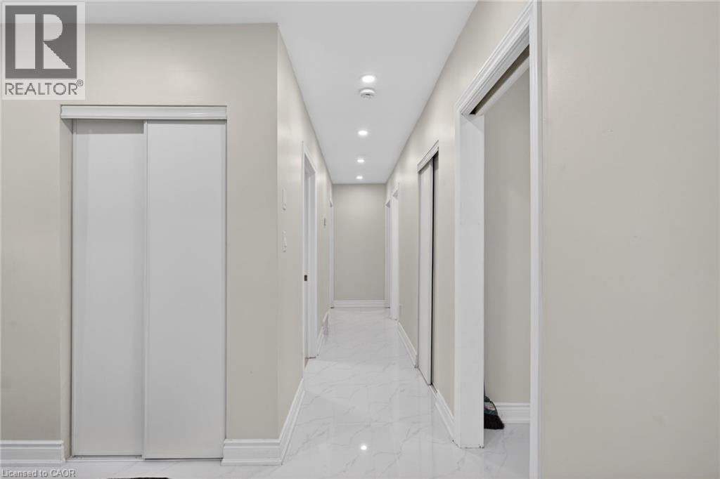 Long hallway featuring recessed lighting, light-colored walls, white baseboards, and glossy white flooring - 53 Nicklin Crescent, Guelph, ON - Indoor Photo Showing Other Room