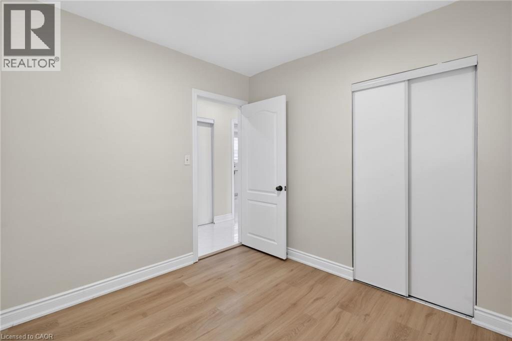 Room featuring wood-finish flooring, light-toned walls, white baseboards, and a white sliding closet door - 53 Nicklin Crescent, Guelph, ON - Indoor Photo Showing Other Room